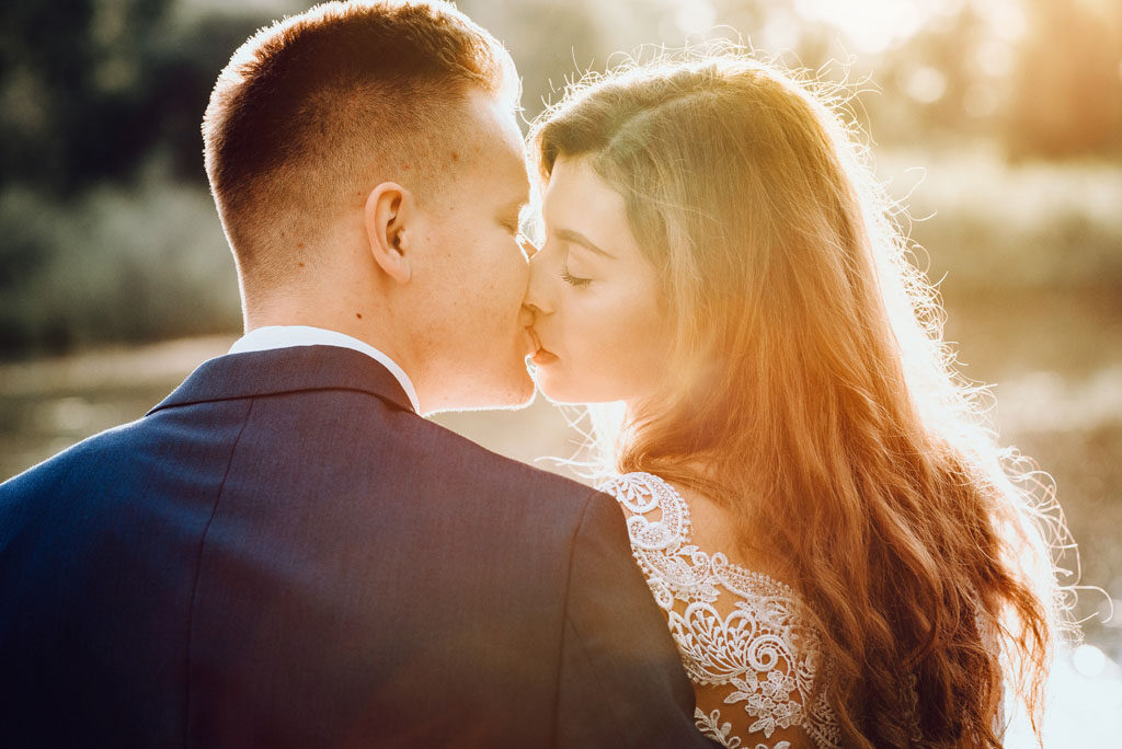 Pocałunek mężczyzny i kobiety to magiczna chwila na sesji plenerowej.